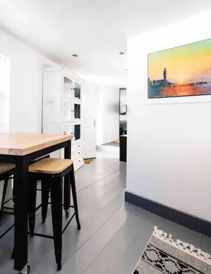 a dining room with a table and a painting on the wall at The Old Stores, Luxury beach side selfcatered holiday cottage above the beach in Porthleven