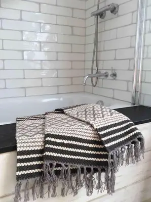 a bath tub with a checkered towel on it at The Old Stores, Luxury beach side selfcatered holiday cottage above the beach in Porthleven
