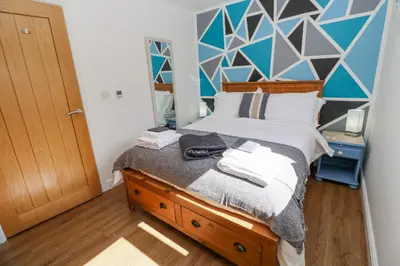 a bedroom with a bed with a blue wall at Kensa in Redruth