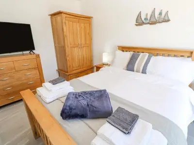 a bedroom with a bed with a television and towels at Kensa in Redruth