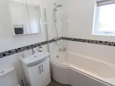 a white bathroom with a sink and a tub and a shower at Kensa in Redruth