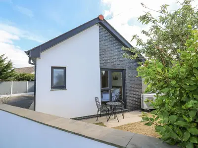 a small white house with a table and a chair at Kensa in Redruth