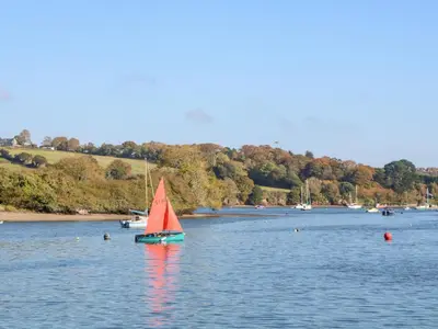 a small red sail boat in the water at Kensa in Redruth