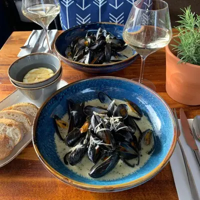two bowls of mussels on a table with glasses of wine at The Lugger Inn in Polruan