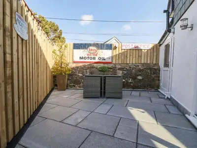 a patio with a fence and a sign on a building at Harvenna Cottage in Bude