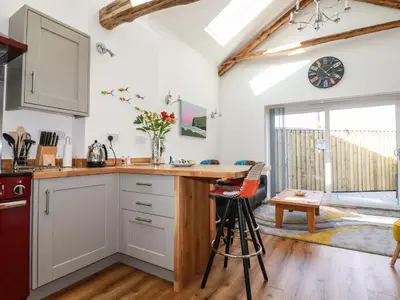 a kitchen with white cabinets and a counter top at Harvenna Cottage in Bude