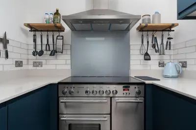 a kitchen with blue cabinets and a stainless steel stove at Marazion Charming Retreat for 6 with Social Garden in Marazion