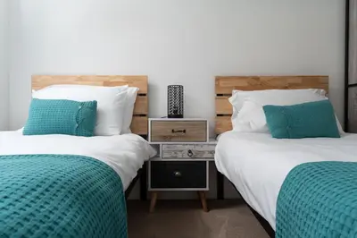 two beds with green and white pillows in a bedroom at Marazion Charming Retreat for 6 with Social Garden in Marazion
