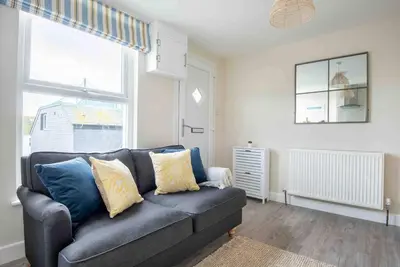 a living room with a blue couch and a window at The Little Loft St Ives in St Ives
