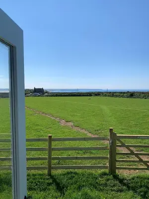a fence in front of a large field at Ewe With A View Sea View Shepherds Huts in Breage