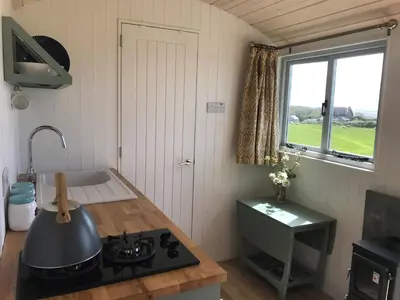 a kitchen with a stove and a sink and a window at Ewe With A View Sea View Shepherds Huts in Breage