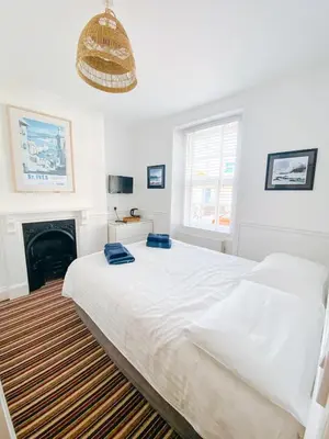 a white bedroom with a bed and a fireplace at Beachside Guesthouse in St Ives