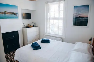 a bedroom with a bed with two blue towels on it at Beachside Guesthouse in St Ives