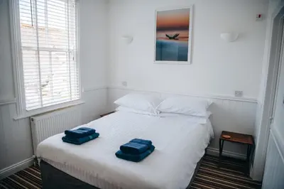 a bedroom with a bed with two blue towels on it at Beachside Guesthouse in St Ives