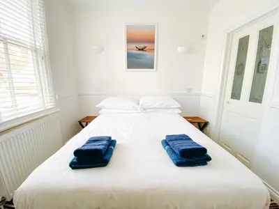 a white bed with two blue towels on it at Beachside Guesthouse in St Ives