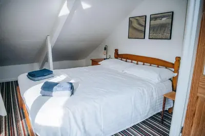 a bedroom with a large white bed in a attic at Beachside Guesthouse in St Ives