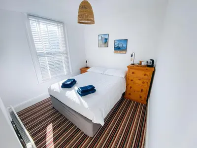 a bedroom with a bed with two blue bags on it at Beachside Guesthouse in St Ives