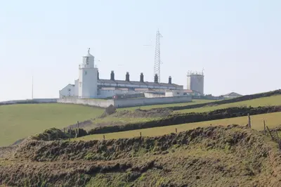 a building on top of a hill with a green field at Ginentonic Cottage in Saint Keverne