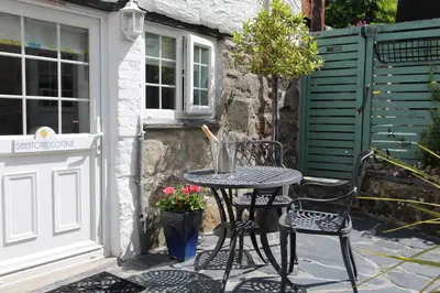 a table and two chairs in front of a door at Ginentonic Cottage in Saint Keverne