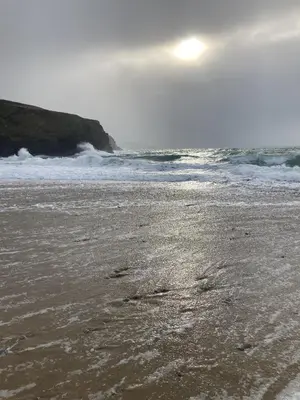 a beach with footprints in the sand and the ocean at Ginentonic Cottage in Saint Keverne