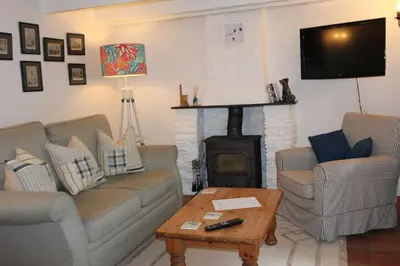 a living room with two couches and a fireplace at Ginentonic Cottage in Saint Keverne