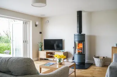 a living room with a wood burning stove at Luxury retreat with hot tub & wood burner - Mylor in Falmouth