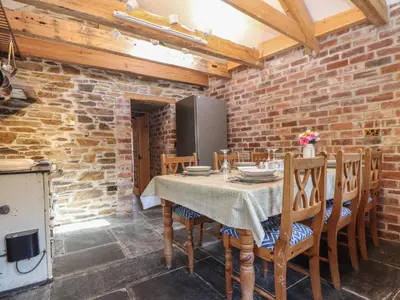 a dining room with a table and chairs and a brick wall at Trewince Manor Cottage in Truro