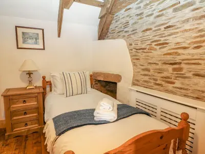 a bedroom with a bed and a brick wall at Trewince Manor Cottage in Truro