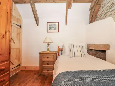 a bedroom with a bed and a lamp on a dresser at Trewince Manor Cottage in Truro