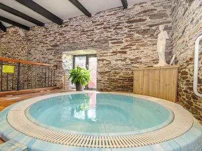 a large swimming pool in a room with a stone wall at Trewince Manor Cottage in Truro