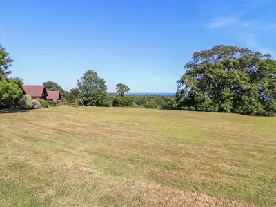 a large grassy field with a house and trees at Trewince Manor Cottage in Truro