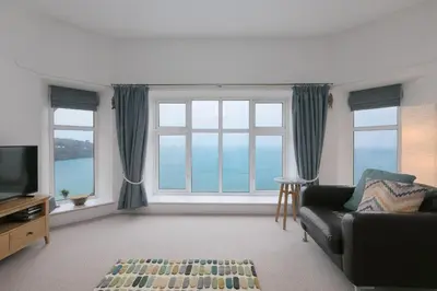 a living room with a couch and a large window at 4 Pentowan Court in St Ives