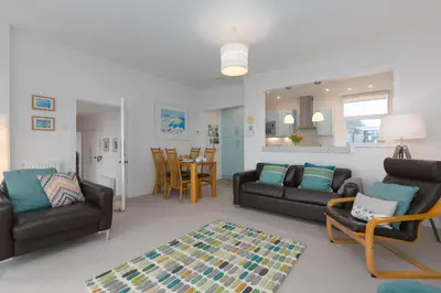 a living room with couches and a dining room at 4 Pentowan Court in St Ives