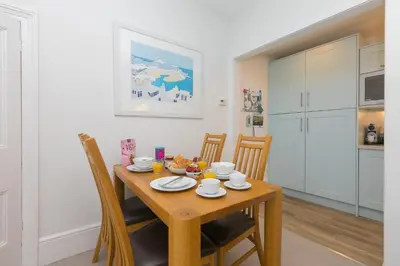 a kitchen and dining room with a wooden table and chairs at 4 Pentowan Court in St Ives