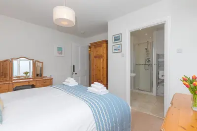 a bedroom with a white bed with a blue blanket at 4 Pentowan Court in St Ives