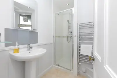 a white bathroom with a sink and a shower at 4 Pentowan Court in St Ives