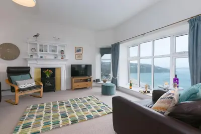 a living room with a couch and a tv and a large window at 4 Pentowan Court in St Ives