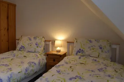 a bedroom with two beds and a table with a lamp at Flat 18 Pochin House in St Austell