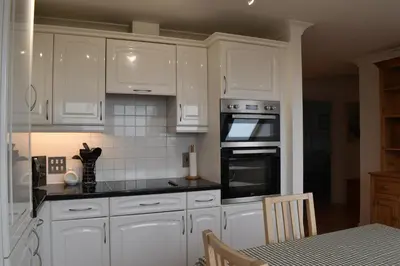 a kitchen with white cabinets and a stove top oven at Flat 18 Pochin House in St Austell