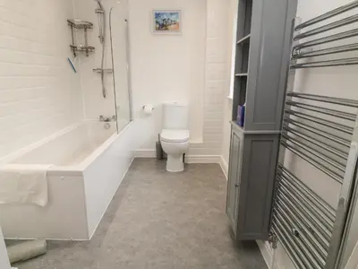 a bathroom with a toilet and a tub and a sink at Brewers Cottage in Looe