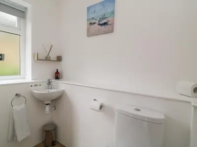 a white bathroom with a sink and a toilet at Brewers Cottage in Looe