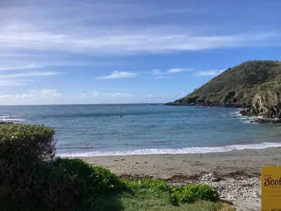 a beach with a person swimming in the ocean at Brewers Cottage in Looe