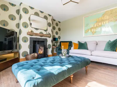 a living room with a blue velvet couch and a fireplace at Chyvounder in St. Agnes