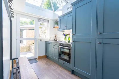a kitchen with blue cabinets and a window at Chyvounder in St. Agnes