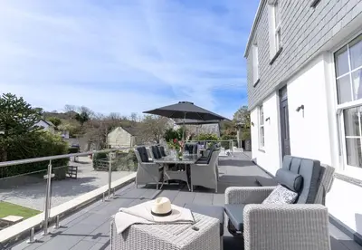 a patio with a table and chairs and an umbrella at Chyvounder in St. Agnes