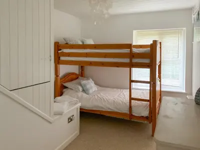 a bedroom with two bunk beds and a window at Castle Cottage in Ruan Lanihorne