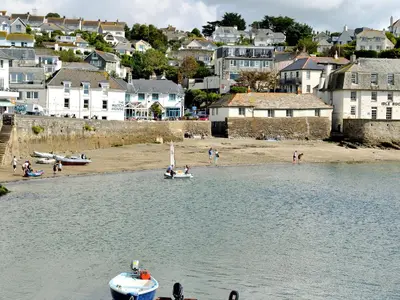 a boat in the water near a beach with houses at Castle Cottage in Ruan Lanihorne