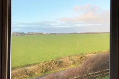 a view of a large green field from a window at Sea View Nook in Porthtowan