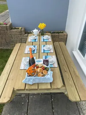 a picnic table with food and a bottle of wine at Surf's Up! Perfect base for holidays or work in Cornwall in Saint Columb Major