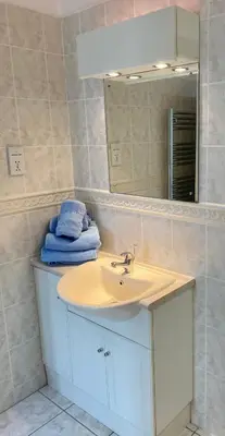 a bathroom with a sink and a mirror and towels at Surf's Up! Perfect base for holidays or work in Cornwall in Saint Columb Major
